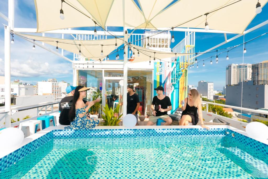 a group of people sitting around a swimming pool on a rooftop at The Backpacker Hostel and spa in Da Nang