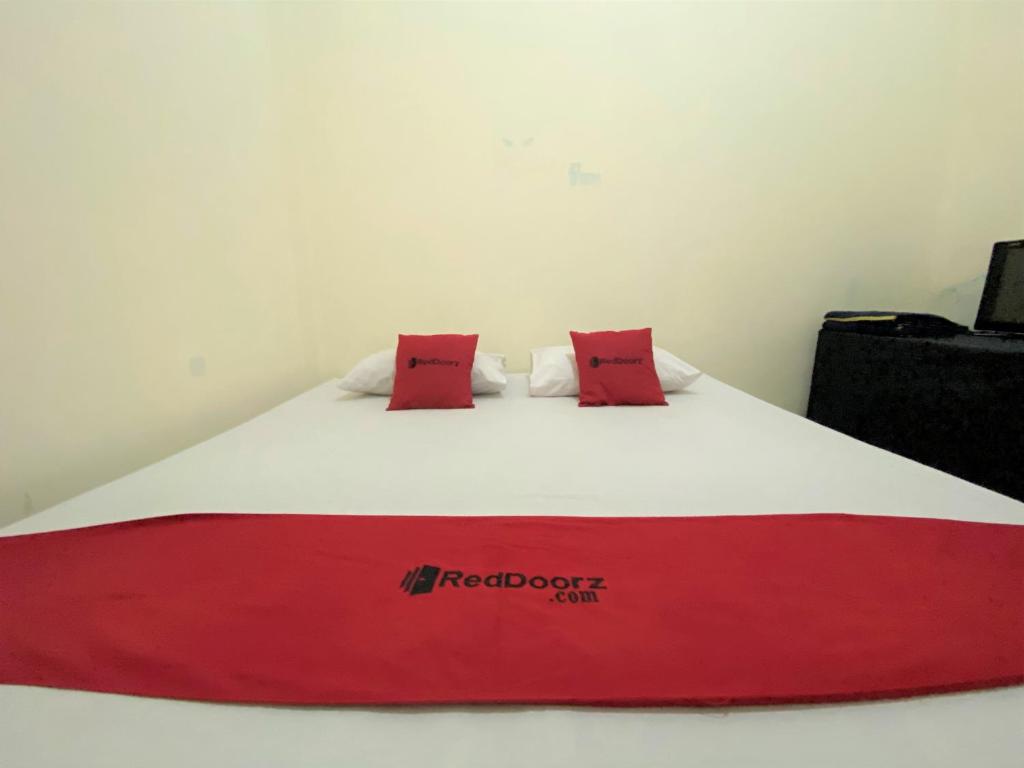 a red and white bed with two red pillows on it at RedDoorz near GOR Lagaligo Palopo in Palopo