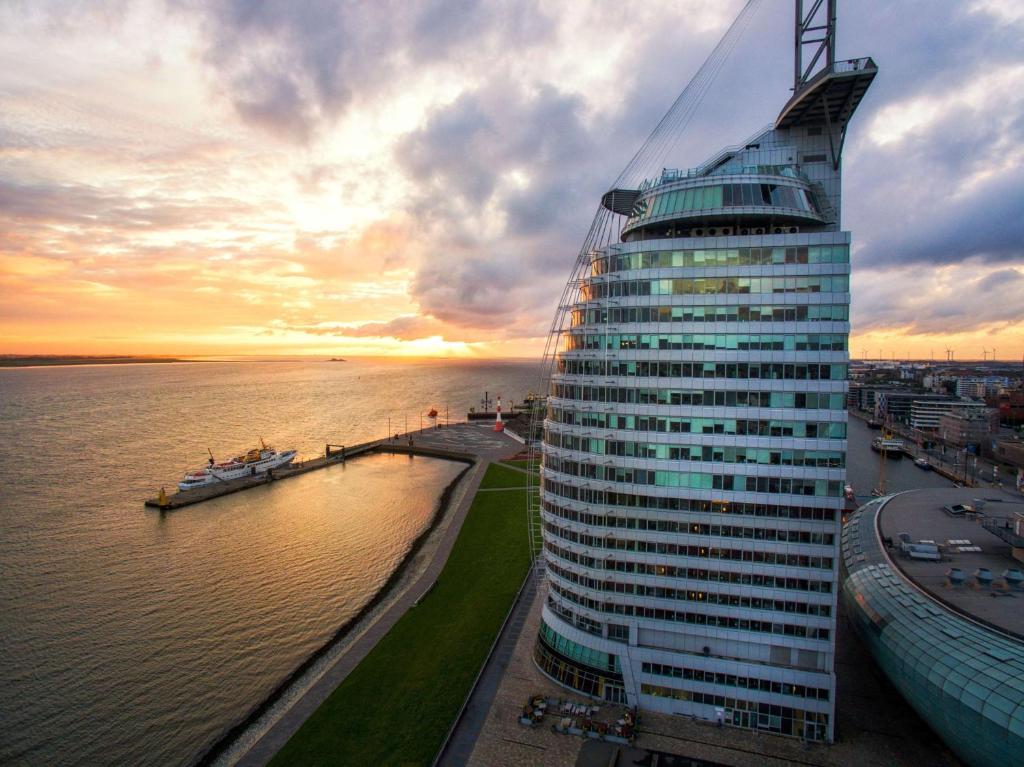 un grand bâtiment à côté d'une masse d'eau dans l'établissement Atlantic Hotel Sail City, à Bremerhaven