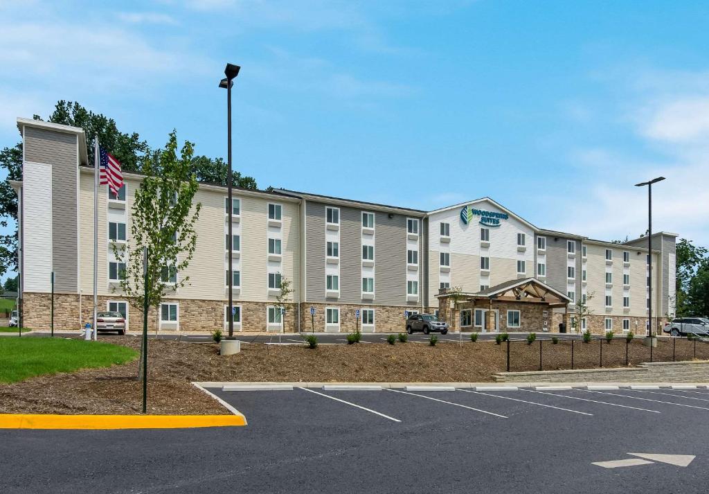 a large building with an american flag in a parking lot at WoodSpring Suites Roanoke in Roanoke