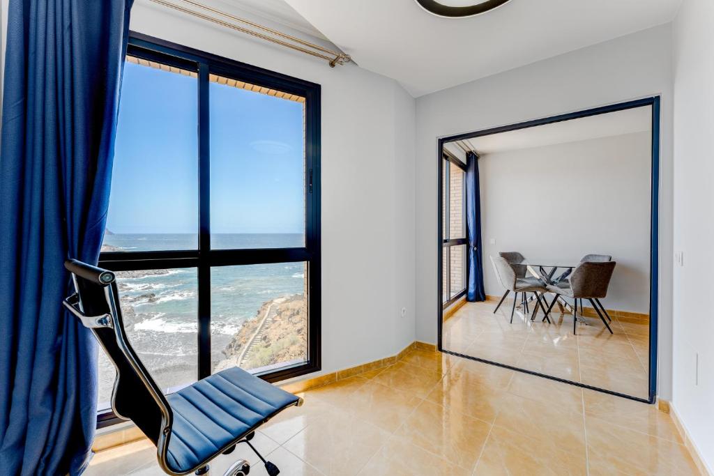 a blue chair in a room with large windows at Stunning sea view in Los Abrigos in Los Abrigos