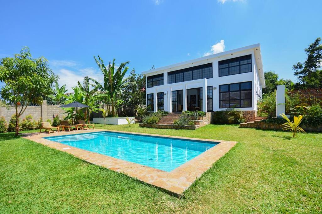 a house with a swimming pool in the yard at Private Villa at the Source of the Nile in Jinja