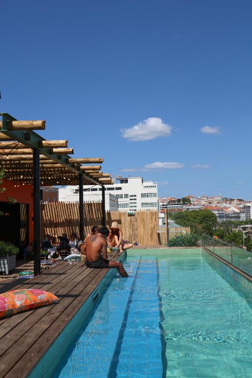 A rooftop pool with loungers, pergola shade and a broad city view.