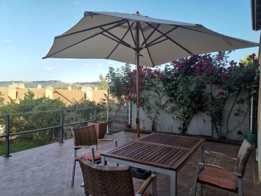 una mesa y sillas con una sombrilla en el balcón en Estancia con jardín entre golf y monte - cerca Logroño, en Sojuela