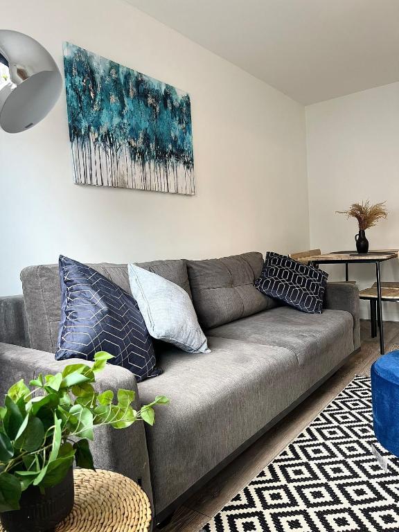 a living room with a gray couch with pillows at Central Watford Duplex in Watford