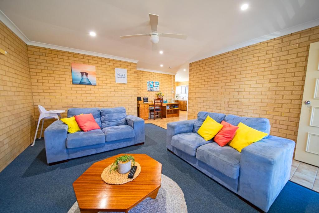 ein Wohnzimmer mit 2 blauen Sofas und einem Tisch in der Unterkunft Comfortable Central Unit in Geraldton