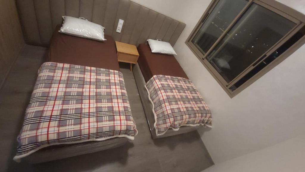 two beds in a room next to a window at Zenata Tower Ain Harrouda Mohemadia in Mohammedia