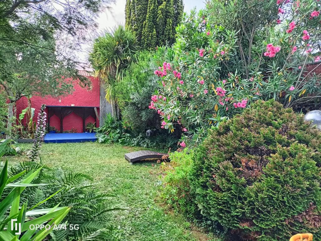 un jardín con flores rosas y un edificio rojo en Maison Cocooning, bord de Sèvre Nantaise, en Nantes