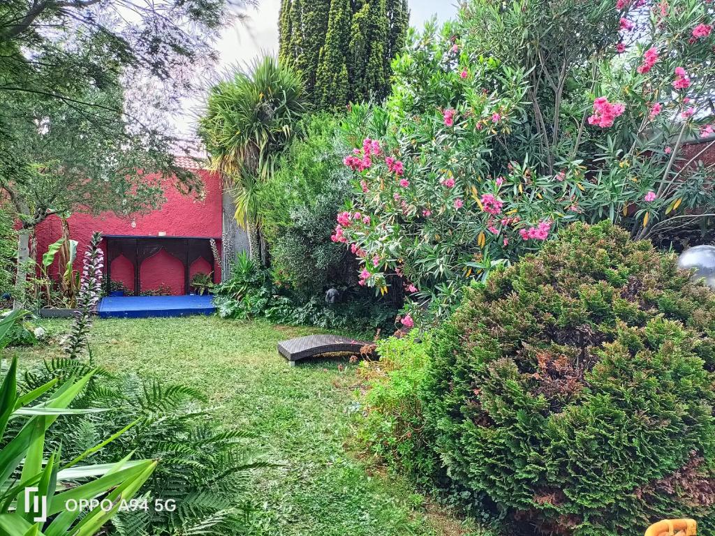 ogród z różowymi kwiatami i czerwonym budynkiem w obiekcie Maison Cocooning, bord de Sèvre Nantaise w mieście Nantes