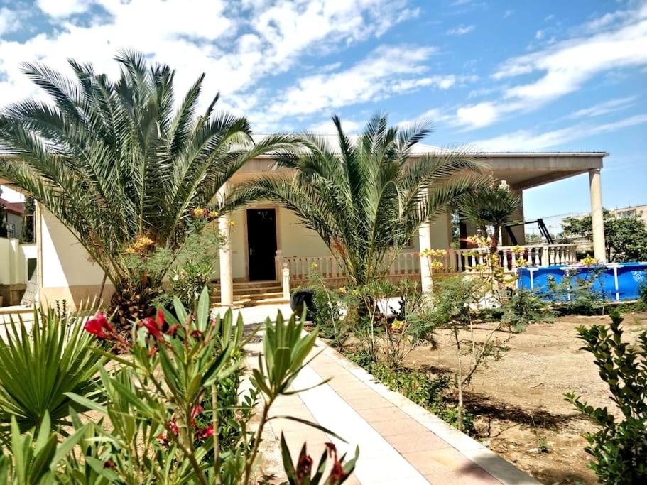 ein Haus mit Palmen im Garten in der Unterkunft Gilavar 3 in Baku