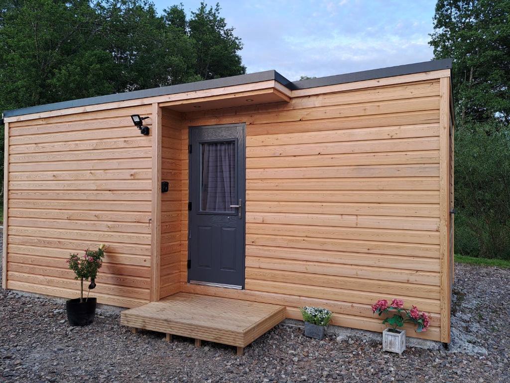 un hangar en bois avec une porte et deux plantes dans l'établissement The Posh Bothy Spean Bridge, à Fort William