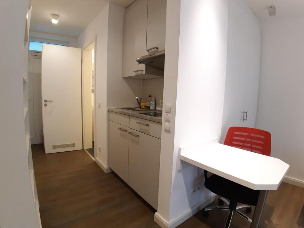 a kitchen with white cabinets and a table and chairs at LEA-Apartments Zentrum Ost mit Stellplatz in Leipzig