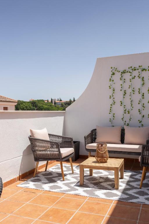 a patio with a couch and chairs and a table at Apartamentos Martalia Áticos Deluxe in Ronda