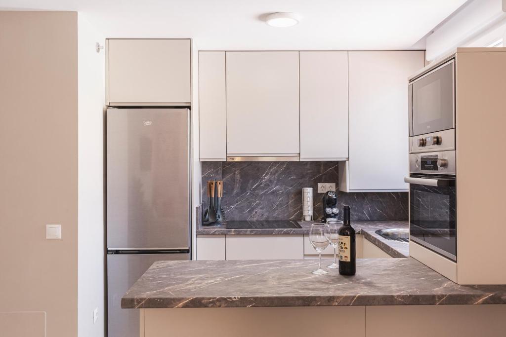 a kitchen with white cabinets and a bottle of wine on a counter at Apartamentos Martalia Áticos Deluxe in Ronda