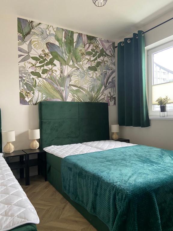 a bedroom with a green bed and a floral wallpaper at Kolorowy Apartament 49b in Debina