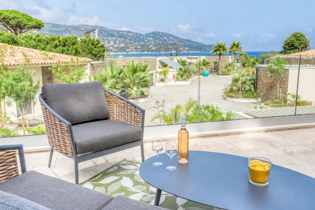 a patio with a table and a chair with wine glasses at Akwabay - Les Villas du Cap in Le Lavandou