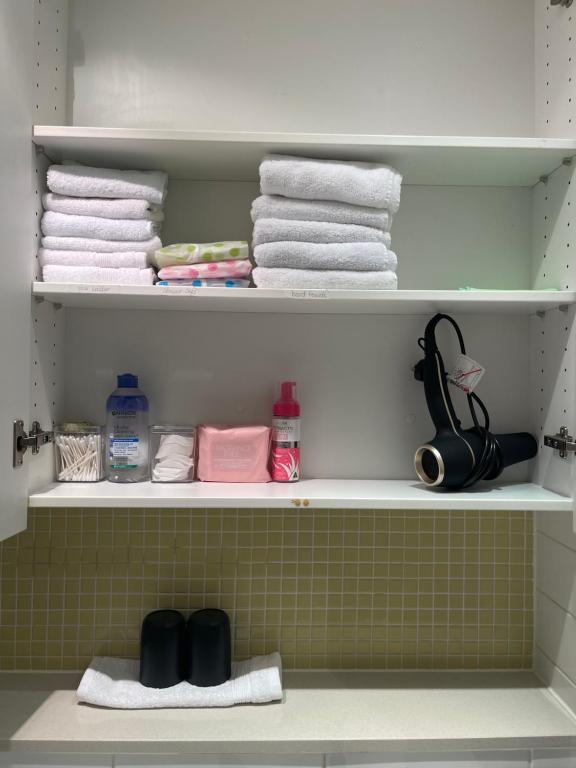 a bathroom shelf with towels and towels at Glenelg resort style beachside apartment in Glenelg