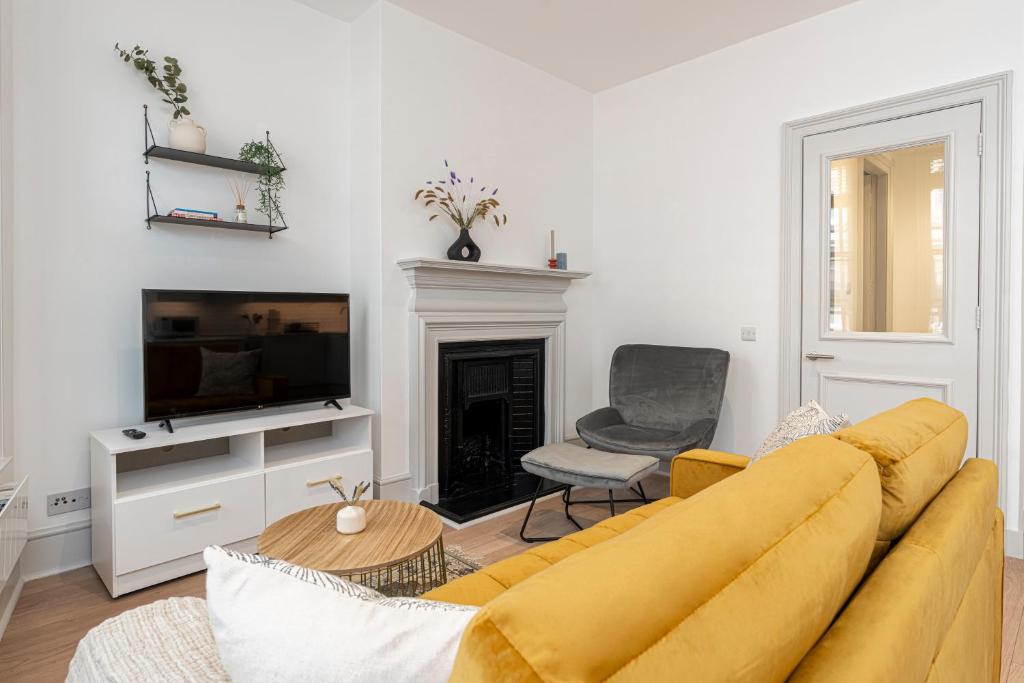 a living room with a yellow couch and a fireplace at ALTIDO Stylish 1 bed flats in Soho, next to Piccadilly Circus in London