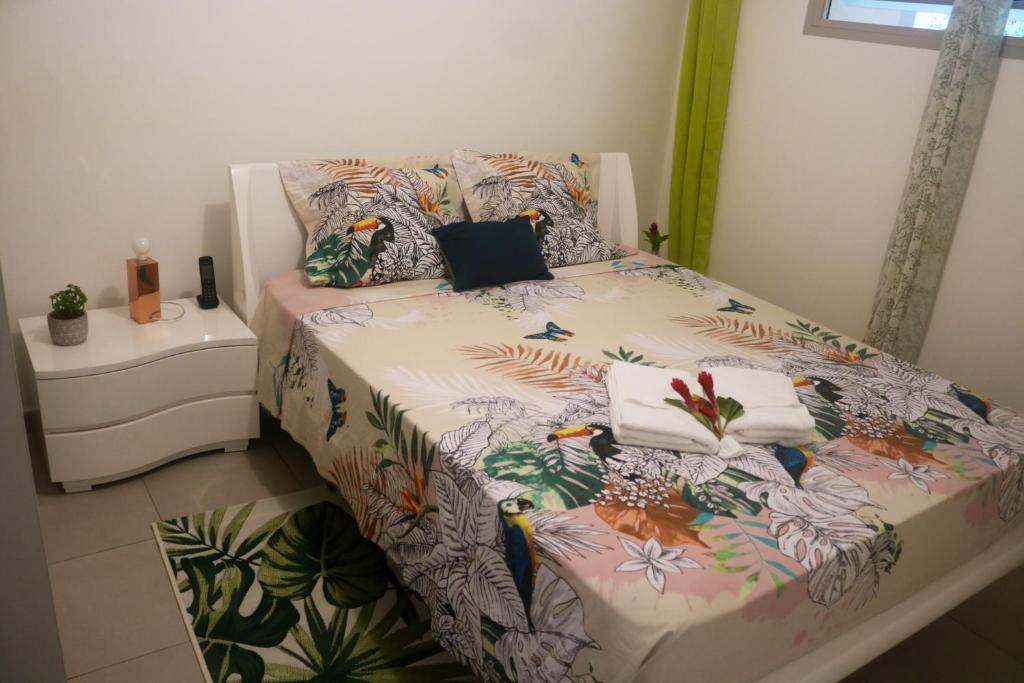 a bedroom with a bed with a floral bedspread and pillows at Appartement d'une chambre avec balcon amenage et wifi a Le Gosier a 1 km de la plage in Le Gosier