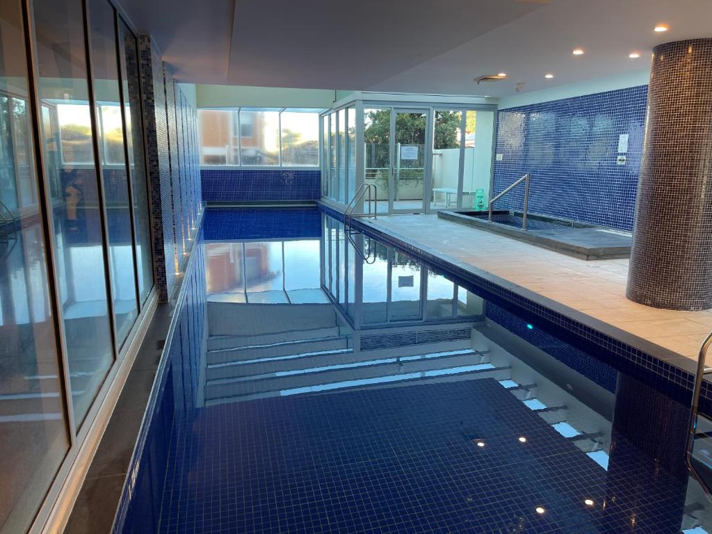 a swimming pool in a building with blue tiles at Glenelg resort style beachside apartment in Glenelg