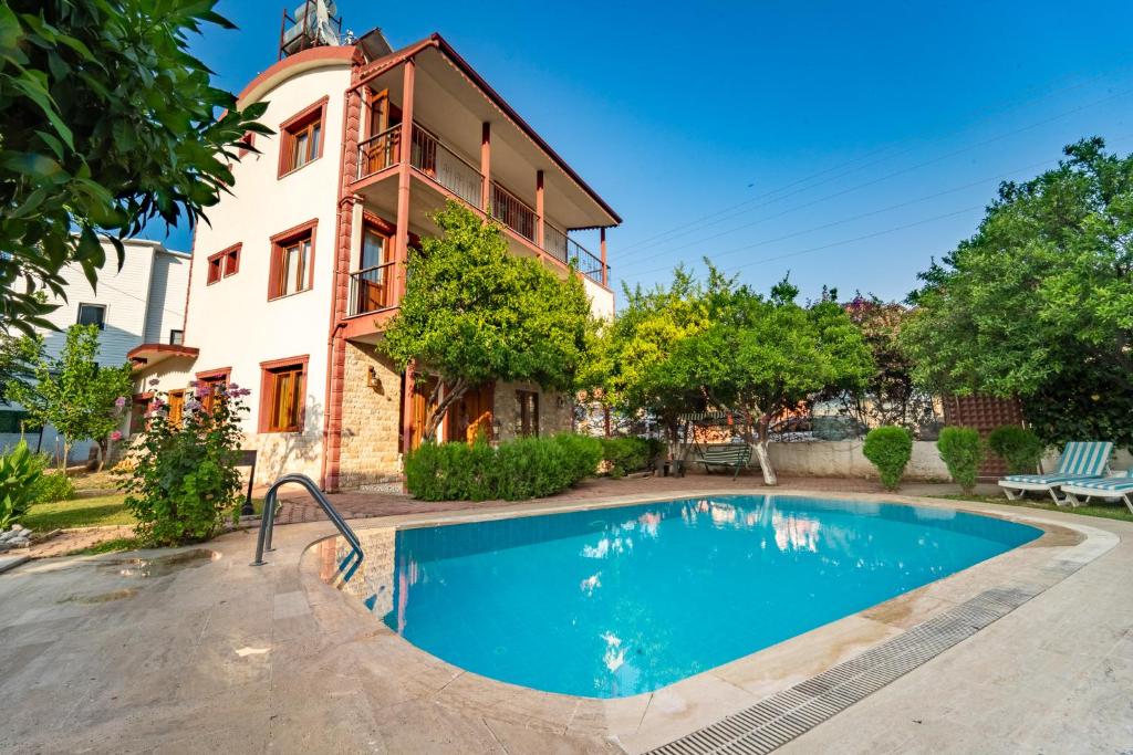 een huis met een zwembad ervoor bij Mavi Deniz Otel in Kemer