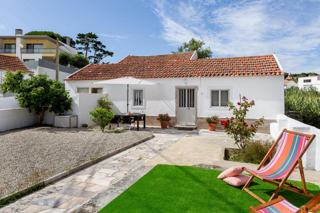 einen Garten mit einer Liegewiese und einem Haus in der Unterkunft ALTIDO Quaint house with Patio in Sintra