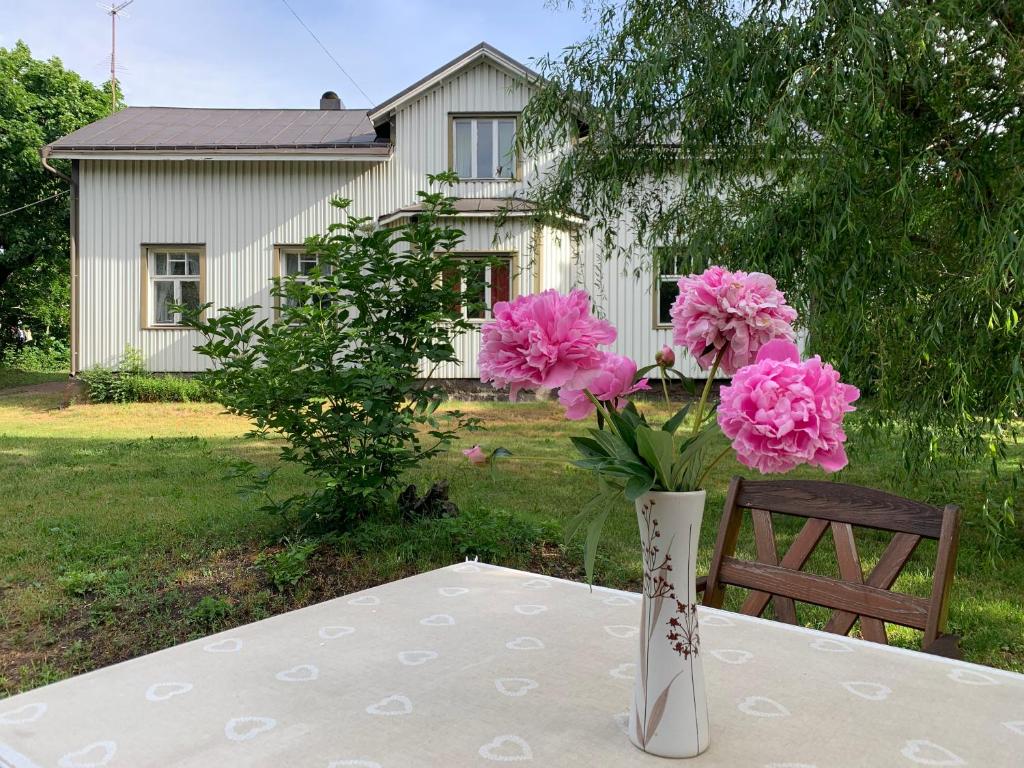 um vaso com flores cor-de-rosa sentado numa mesa em Uppleva att bo på en gammal gård em Kumlinge