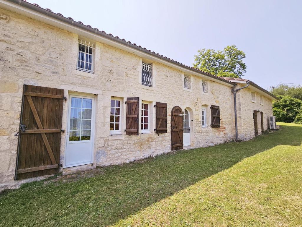 an old stone building with doors and a grass yard at Gîte Le creux du loup in La Couronne