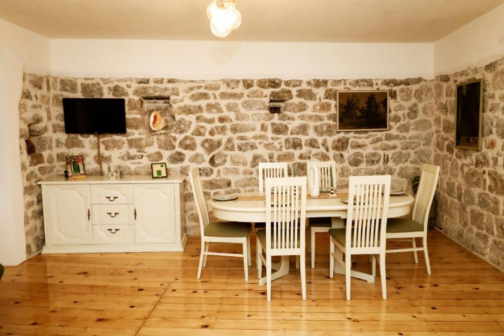 een eetkamer met een stenen muur en een tafel en stoelen bij Apartment Nada Smodlaka in Tivat