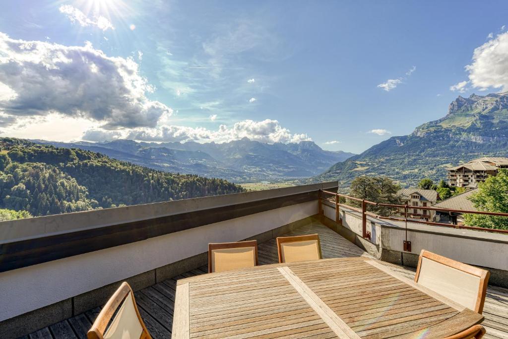 une table et des chaises en bois sur un balcon avec des montagnes dans l'établissement Les Terrasses de Bel Alp, à Saint-Gervais-les-Bains
