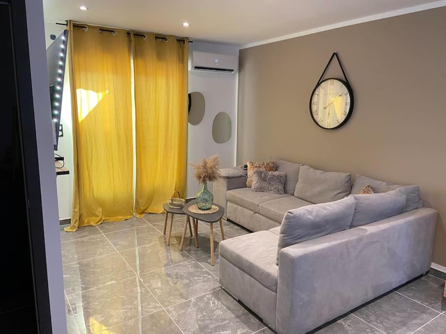 uma sala de estar com um sofá e um relógio na parede em Maison avec jacuzzi em Orange