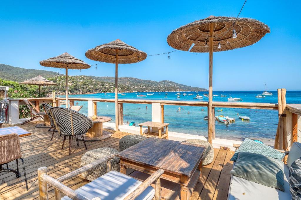 a deck with chairs tables and umbrellas and the ocean at Akwabay - Les Villas du Cap in Le Lavandou