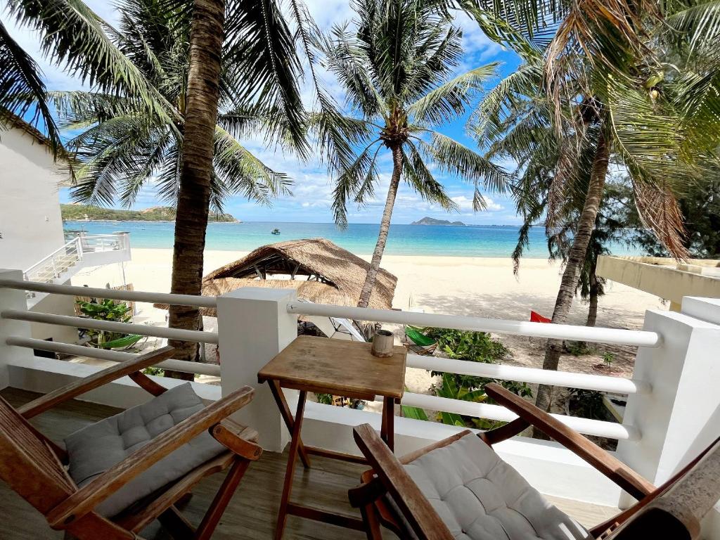 Lucky Spot Beach Bungalow في Song Cau: بلكونه فيها كراسي وطاولة والشاطئ