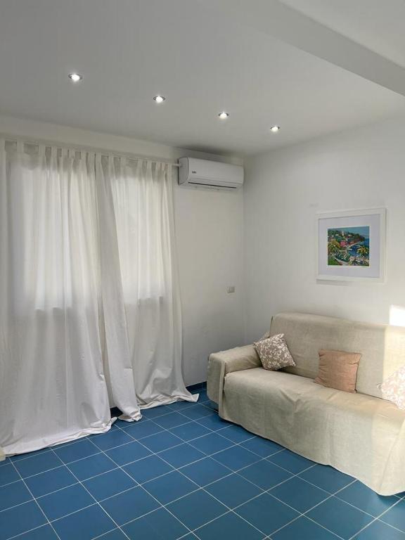 sala de estar con sofá y cortinas blancas en Archiammare Sea, en Reitani