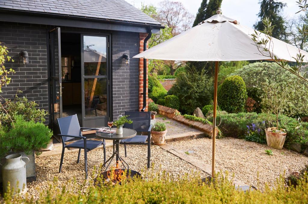 a patio with an umbrella and a table and chairs at The Tiny House in Shootend