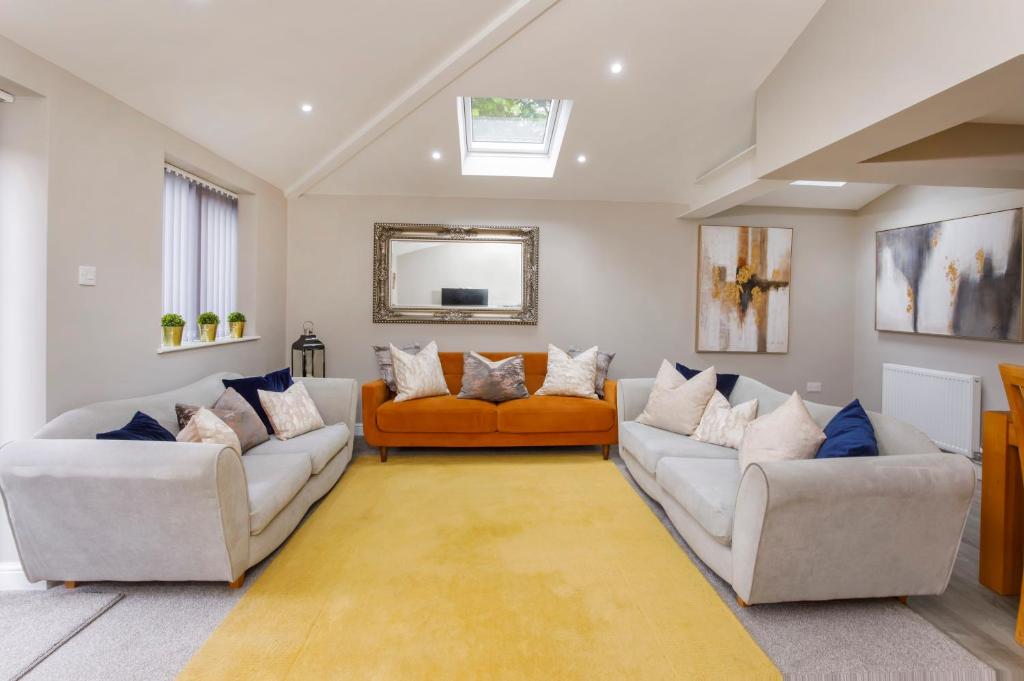 a living room with two couches and an orange couch at Hollis House York- 4 bedroom with free parking in Strensall