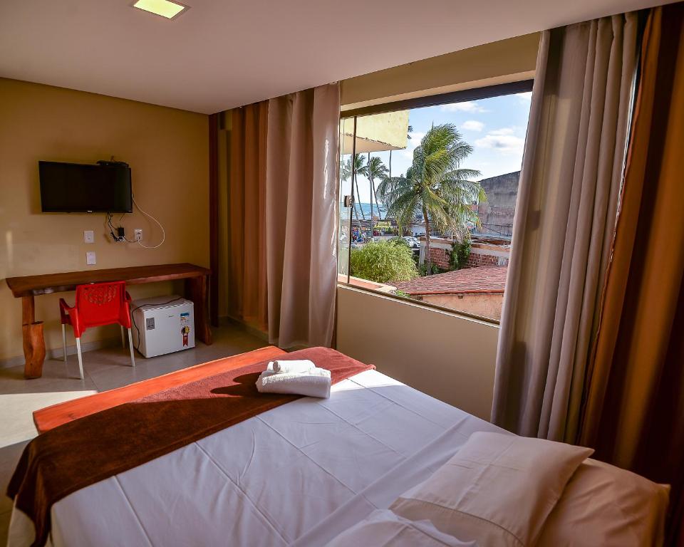 a bedroom with a bed and a large window at Cocco Pousada in Maragogi