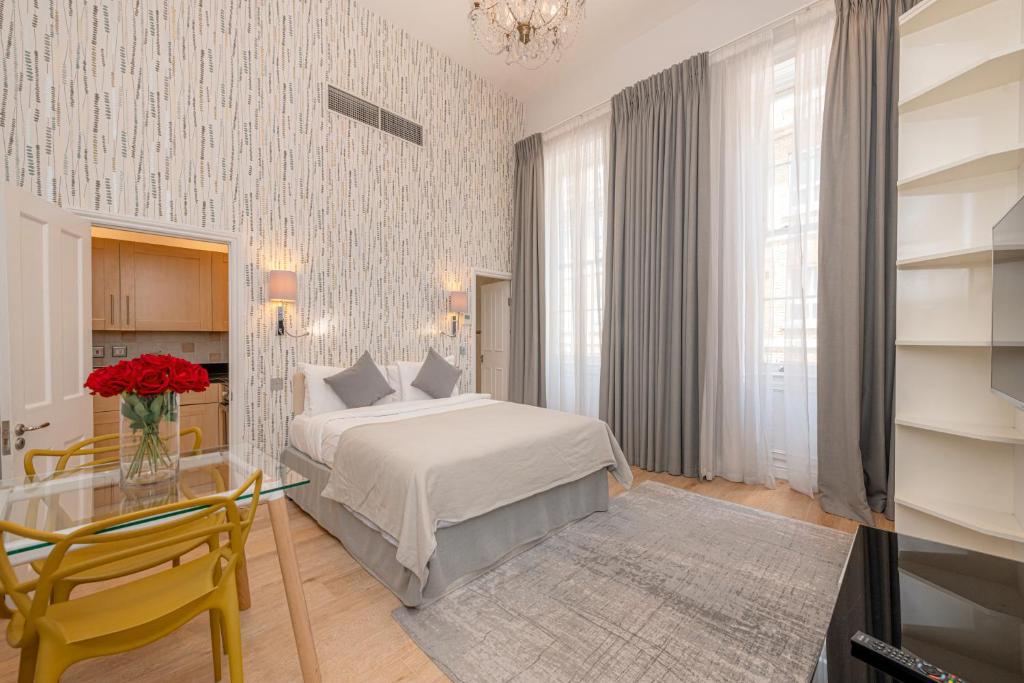 - une chambre avec un lit blanc et une table en verre dans l'établissement 17 Hertford Street, à Londres