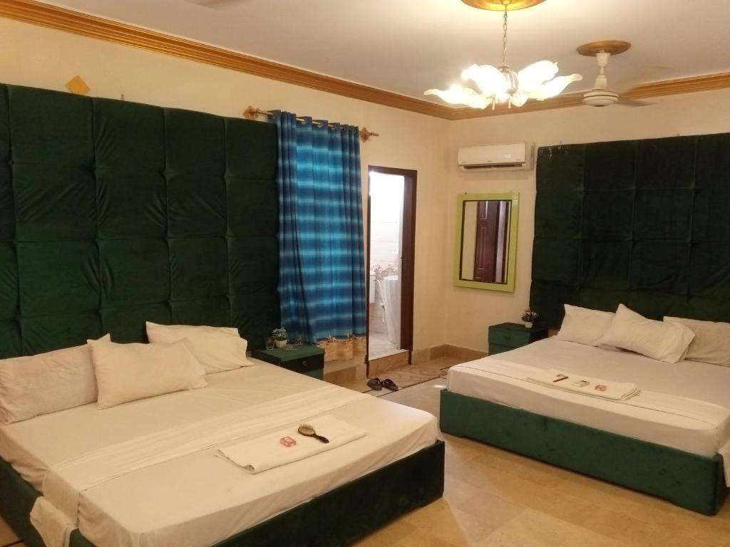 1 dormitorio con 2 camas y ventana grande en Johar Hill view Guest House, en Karachi