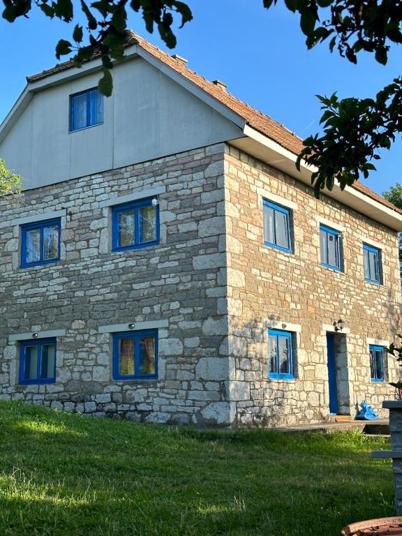 a stone house with blue windows on the side of it at Etno kuća Krvavac in Pljevlja