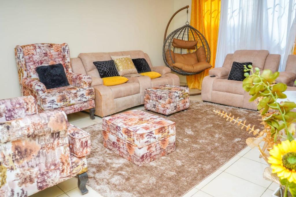 una sala de estar con sofás y reposapiés en Lux Suites Greatwall Getaway Apartments en Machakos