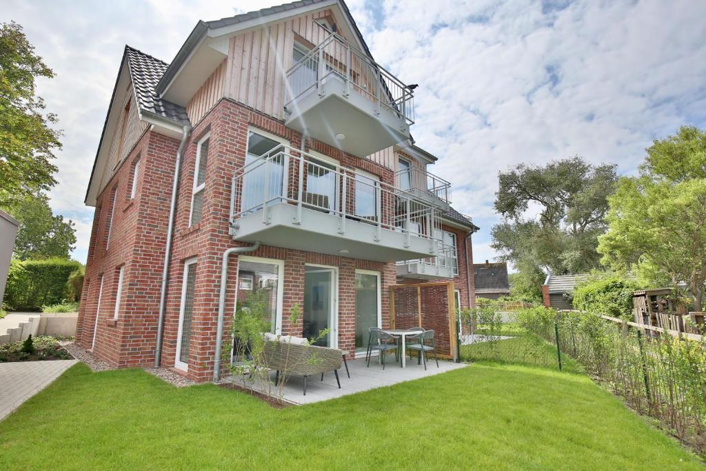 ein Backsteinhaus mit Balkon und Rasen in der Unterkunft Haus Sophie - Wohnung 2 mit Terrasse in Wangerooge