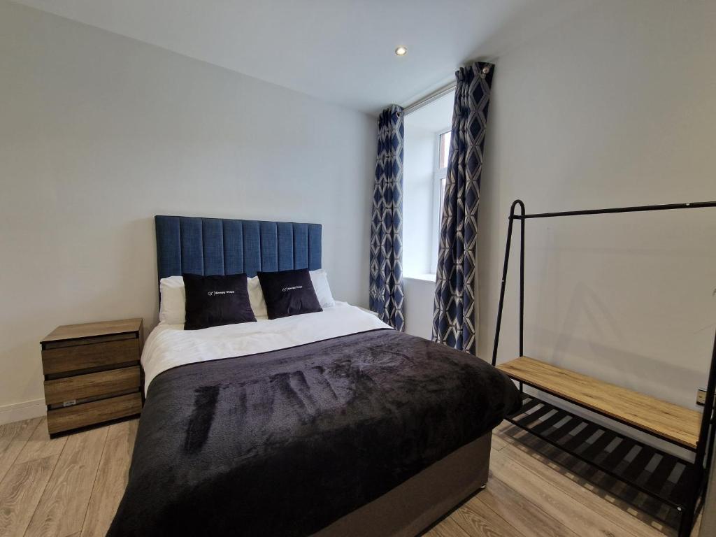 Schlafzimmer mit einem großen Bett mit blauem Kopfteil in der Unterkunft Apartment 4 Tynte Hotel. Mountain Ash. Just a short drive to Bike Park Wales in Quakers Yard
