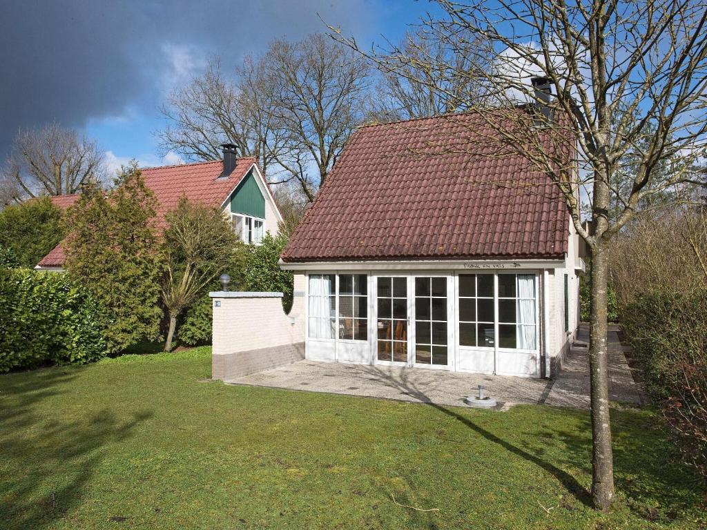 uma pequena casa branca com um telhado vermelho em House suitable for the disabled near Hellendoorn em Hellendoorn