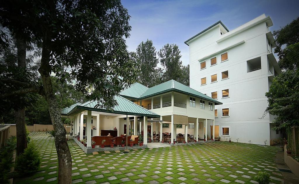duży biały budynek z trawnikiem przed nim w obiekcie Peppervine Hotel w mieście Thekkady