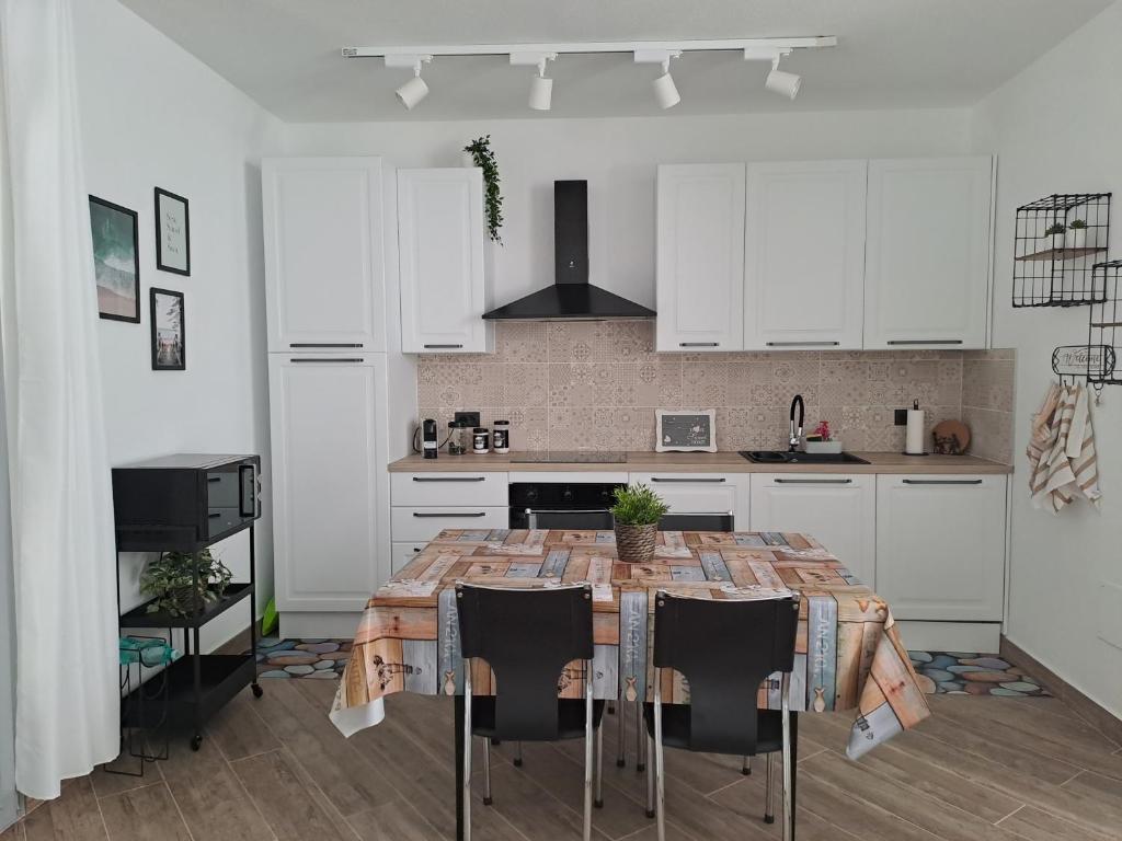 a kitchen with a table with chairs and white cabinets at Suite Da Gabry 2 in Olbia