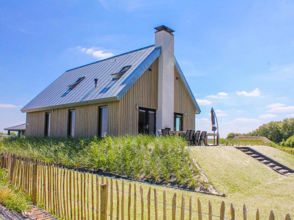 un bâtiment avec un toit bleu et une clôture dans l'établissement Wellness lodge with sunshower, à Tholen