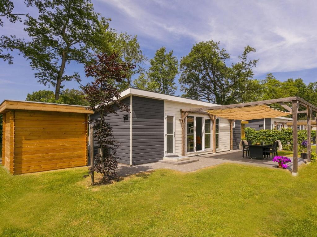 una piccola casa con patio nel cortile di Sunlit Chalet by the Pond a Lochem