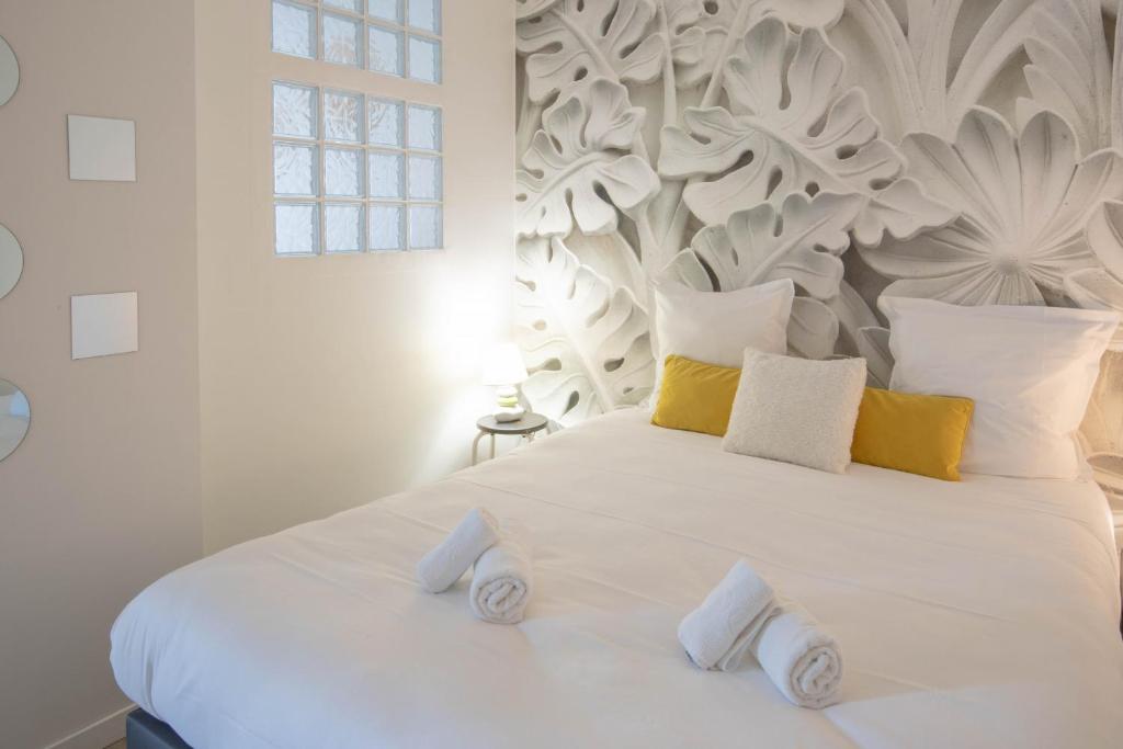 uma cama branca com almofadas amarelas e brancas em L Ecrin L4 3 min centre balcon em Annecy