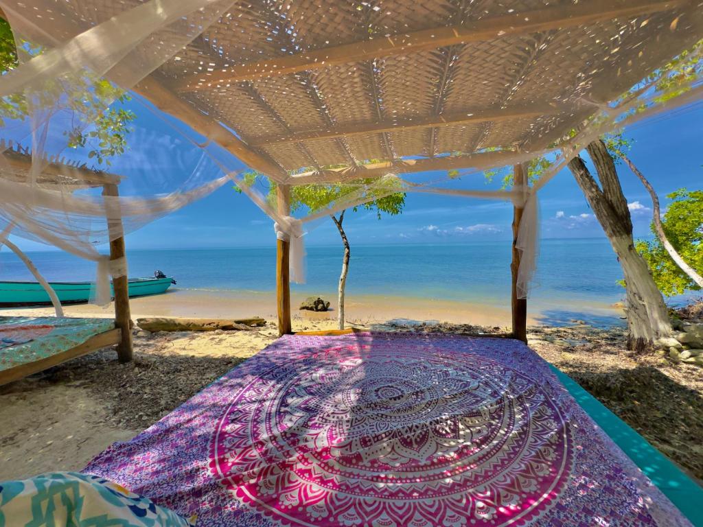 a bed on a beach with the ocean in the background at El Cocotal Tintipán By Ashram in Tintipan Island